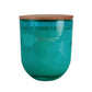 Vela grande en vaso de cristal de color  y tapa de madera con tres mechas.